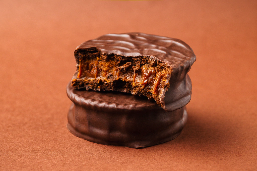 Alfajor Porteño meio amargo mordido, com recheio aparente